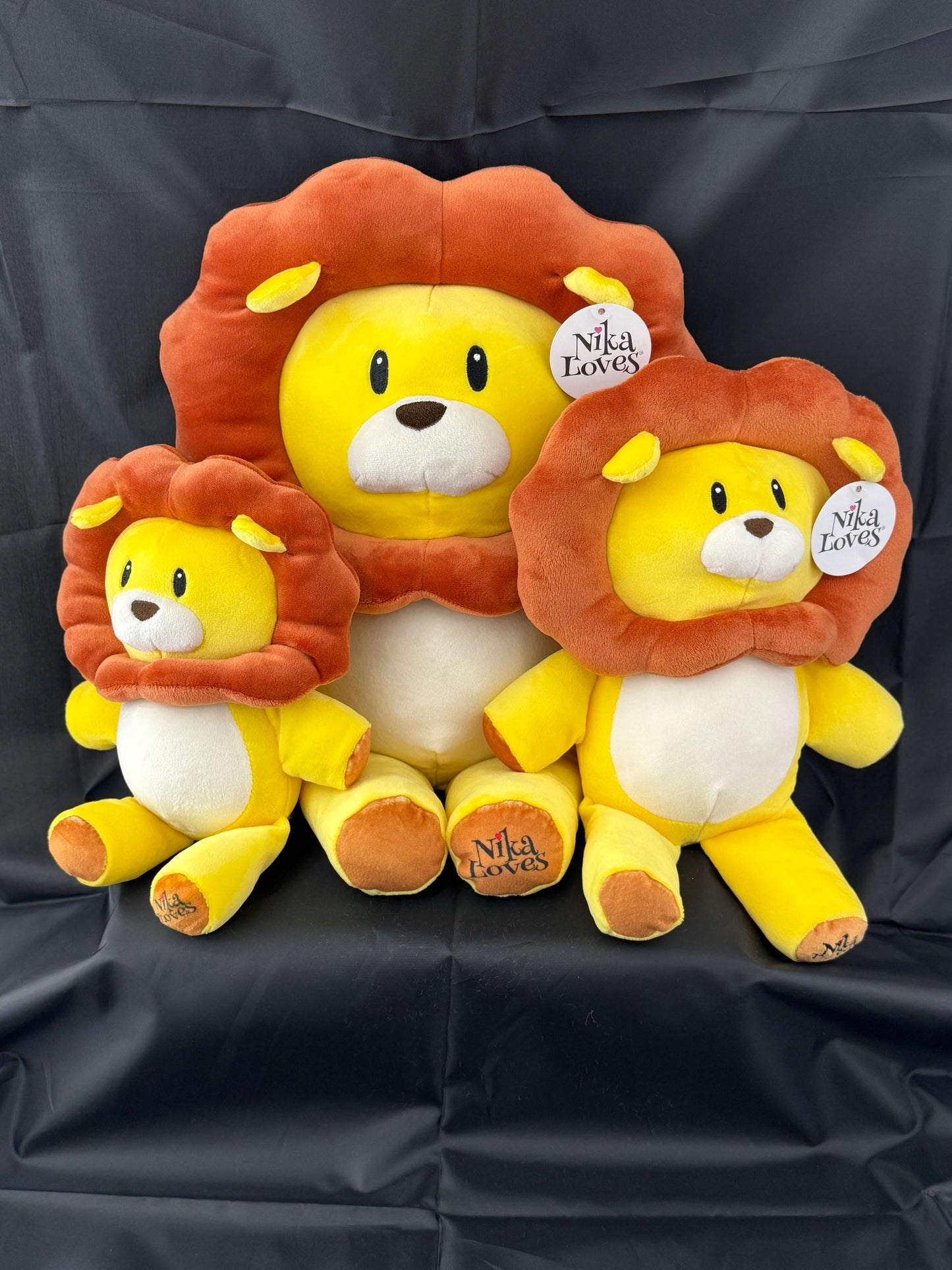 Trio of 18" Leo the Lion plush stuffed animals with vibrant yellow bodies and detailed brown manes, inspired by the "Nika Loves" book series.